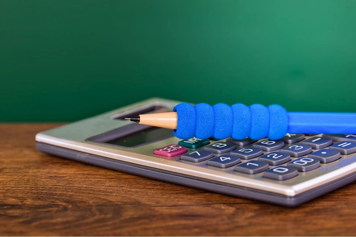 Blue pencil resting on a calculator for budget planning