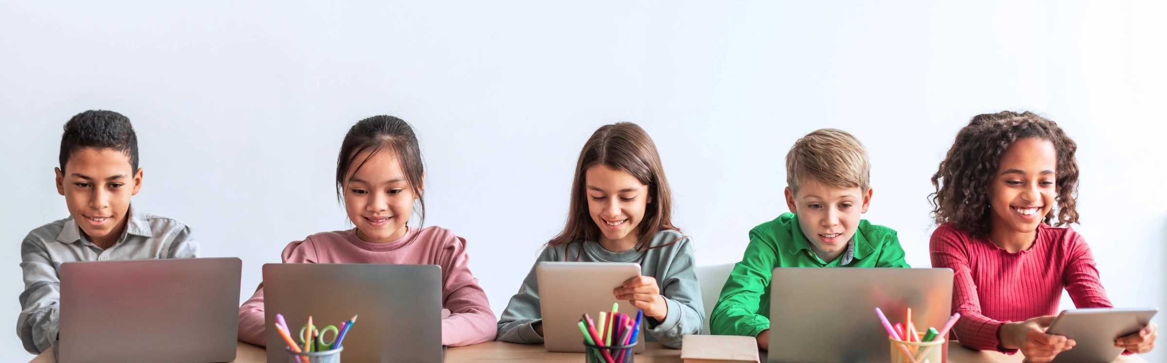 Elementary students using laptops together in a classroom