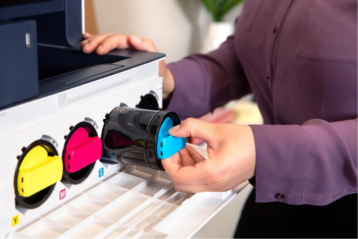 Technician replacing a blue toner cartridge in an office printer