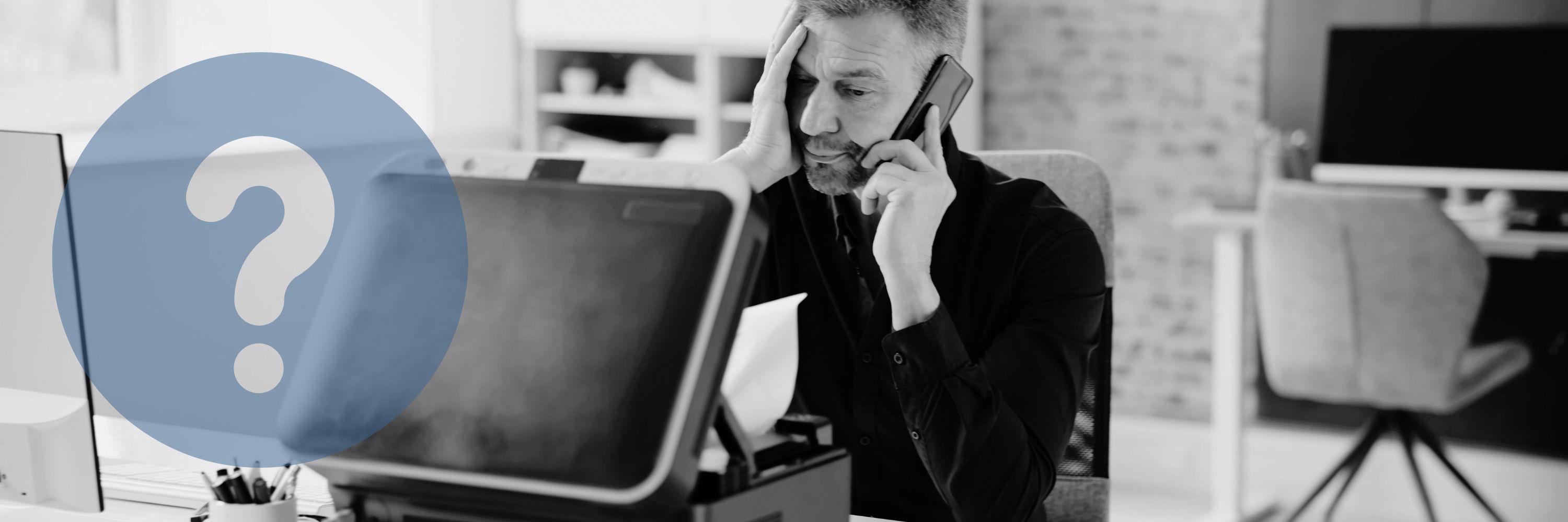 A man on the phone in front of a faulty printer 