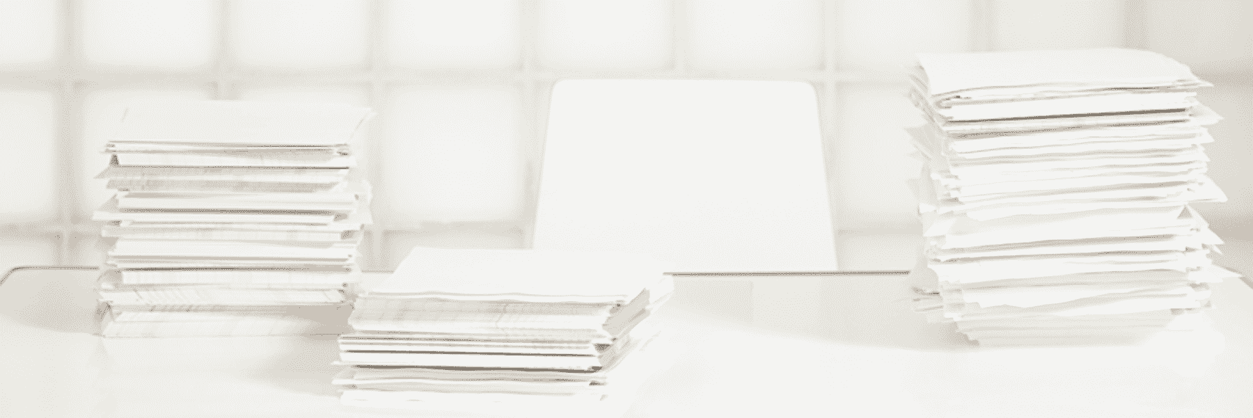 Stacks of paper on top of a white desk 