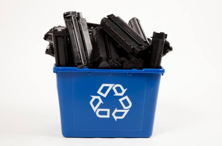 A recycling bin full of old toner cartridges