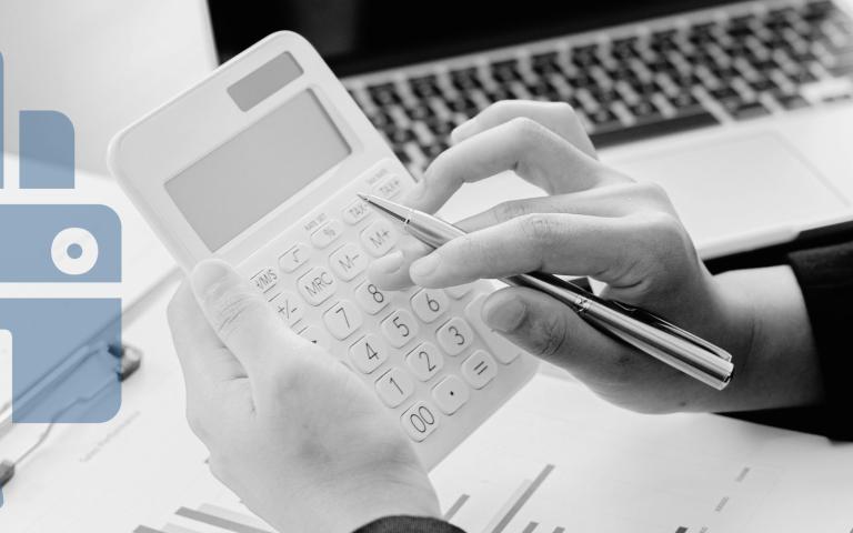 A person calculating a budget with calculator, paper, and laptop