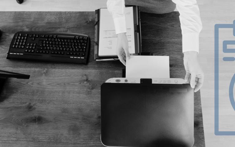 Woman getting a document from a printer on a desk