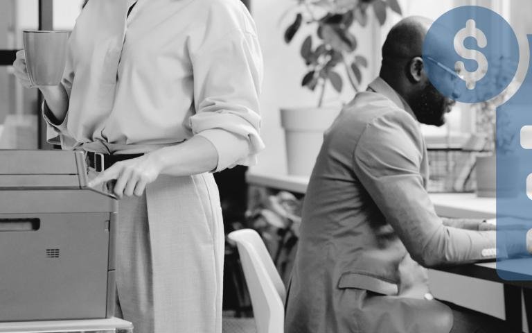 Woman and man in medium-sized office using printer and laptop