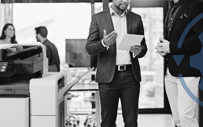 People holding papers in front of a printer