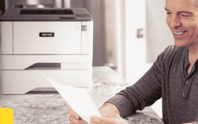Person smiling while looking at a piece of paper next to the Xerox B310