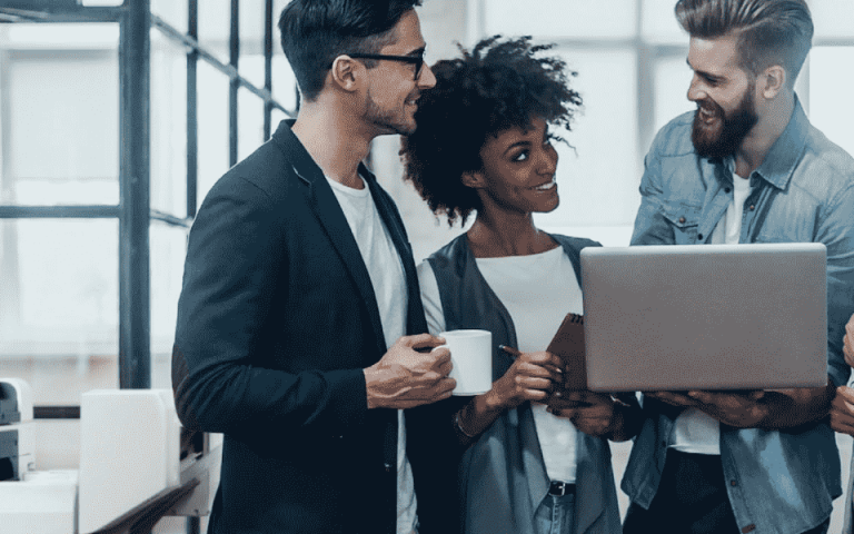 Four people gathering around a laptop with the Xerox VersaLink C7125 in the background