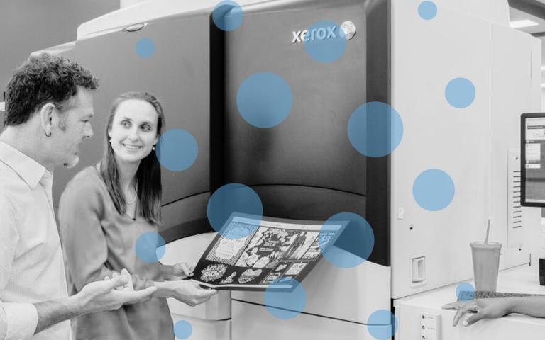 People looking at a print in front of a Xerox digital press