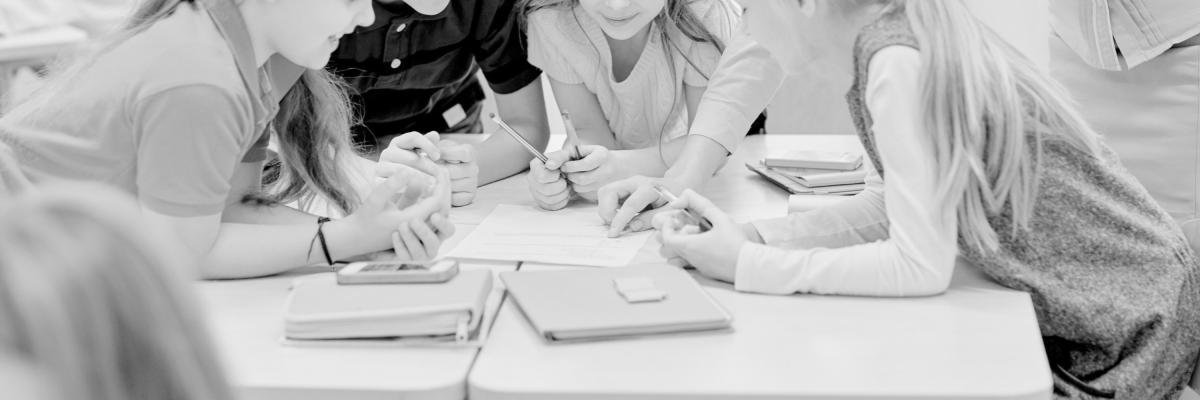 Kids in a classroom with paper assignments on table