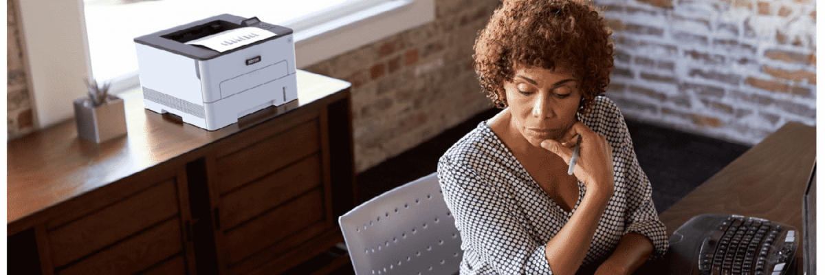 A person sitting at a desk with the Xerox B230 in the background