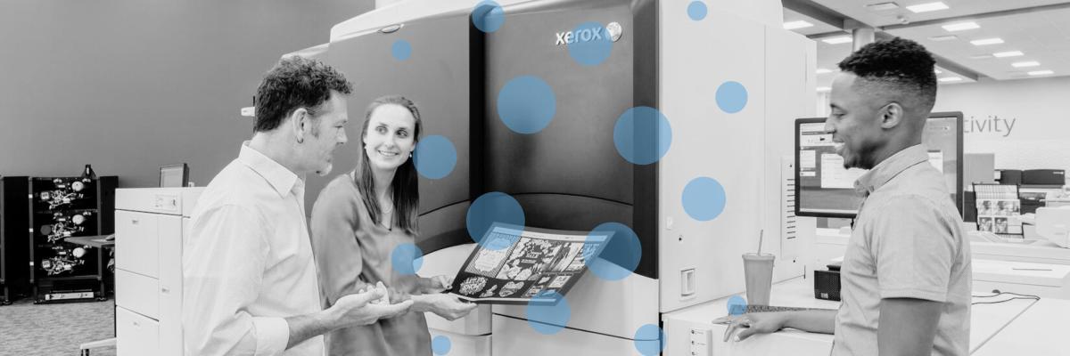 People looking at a print in front of a Xerox digital press