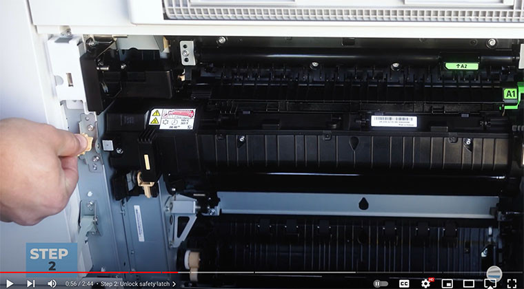 Printer technician lifts latch and slides pin back on the fuser of Xerox AltaLink printer