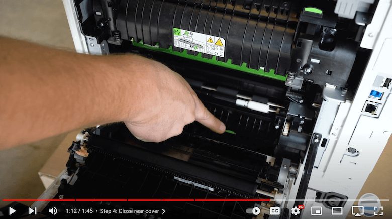 A printer technician points to the green sticker on the back of a Xerox printer