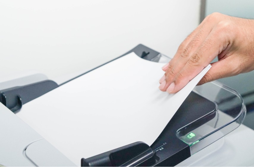 A person putting paper into automatic paper feed on printer to scan