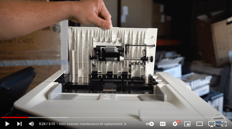 A printer technician lifts open the scanner cover on a printer