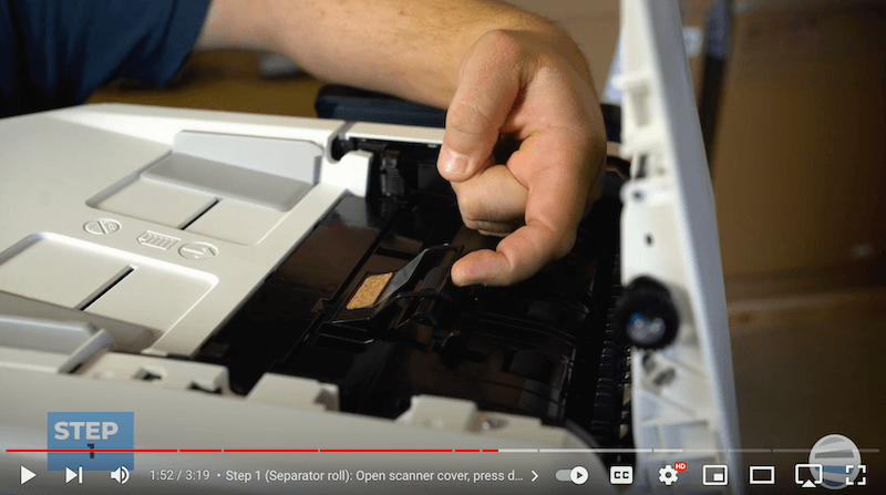 A printer technician lifts the black cover of the separator roll assembly